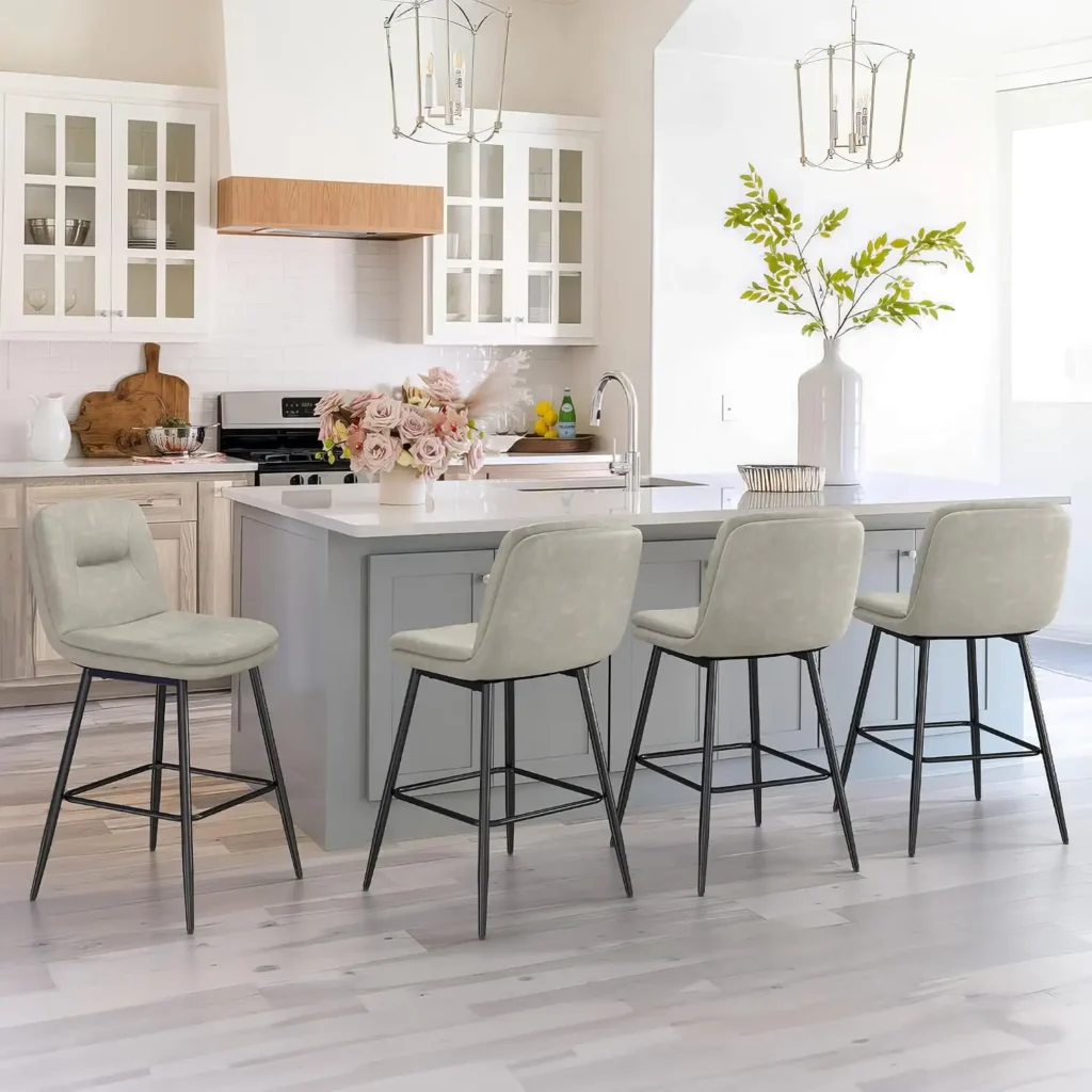 Modern kitchen island with four upholstered counter stools featuring cushioned backrests, padded seats, and integrated footrests in a bright white kitchen.