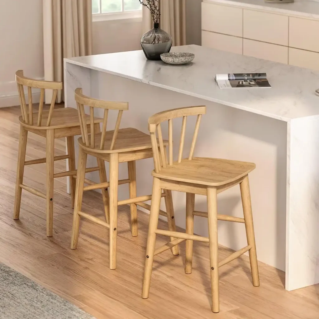 Three natural wood counter stools with slatted backrests and footrests arranged at a white marble kitchen island.