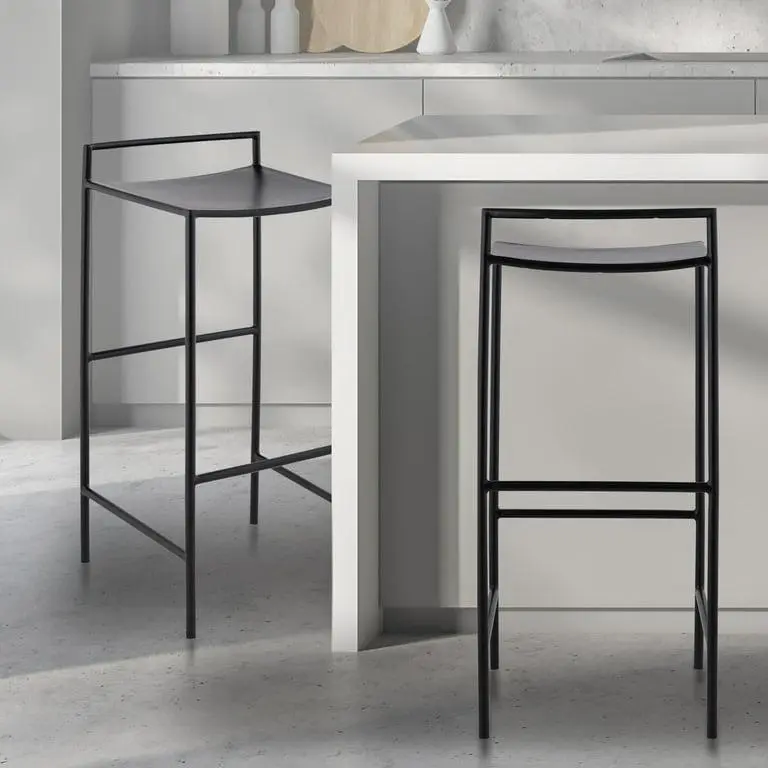 Black metal counter stools with slim frames, curved seats, integrated backrests, and footrests in a modern minimalist kitchen.