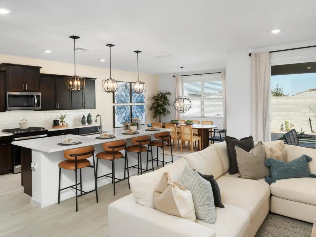 Open-plan kitchen with brown counter stools, a wooden dining table and chairs, and a neutral living room connected in one cohesive space.