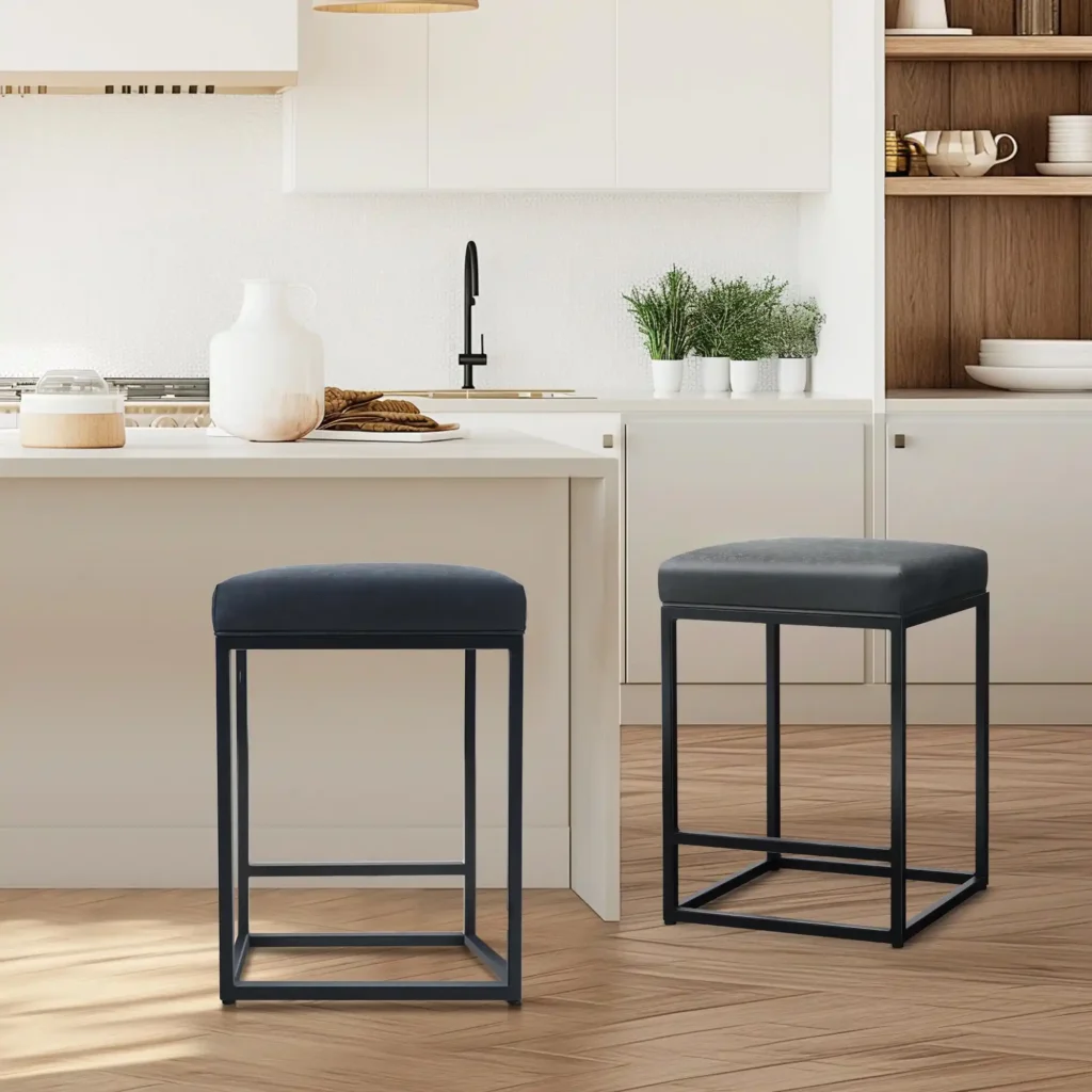 Two compact armless counter stools with padded seats and slim black metal frames positioned at a small kitchen island.